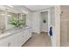 Bright bathroom with double vanity, white cabinetry, stone countertops, and walk-in shower at 12448 Golden Sage Dr, Sarasota, FL 34238