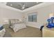 Calm bedroom featuring tray ceiling, window, neutral colors, and wood-style tile flooring at 12448 Golden Sage Dr, Sarasota, FL 34238