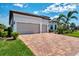 Attractive single-level home with a two-car garage, brick driveway, and well-maintained front yard with palm trees at 12448 Golden Sage Dr, Sarasota, FL 34238