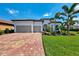 Charming single-story home with lush landscaping, a brick driveway, and a two-car garage offering curb appeal at 12448 Golden Sage Dr, Sarasota, FL 34238