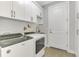Bright laundry room with white cabinetry, modern washer and dryer, and convenient sink area at 12448 Golden Sage Dr, Sarasota, FL 34238