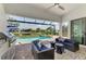 Covered patio with an outdoor kitchen, comfortable seating, and a view of the sparkling pool and spa at 12448 Golden Sage Dr, Sarasota, FL 34238