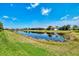 Backyard pond view surrounded by manicured green lawn and houses with lush landscaping in a serene residential neighborhood at 12448 Golden Sage Dr, Sarasota, FL 34238