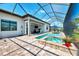 Relaxing screened-in pool and spa area featuring an outdoor kitchen, patio seating, and a scenic backyard view at 12448 Golden Sage Dr, Sarasota, FL 34238