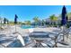 Resort style pool with many lounge chairs, tables and umbrellas with palm trees in the background on a bright sunny day at 12448 Golden Sage Dr, Sarasota, FL 34238