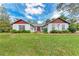 Charming one-story home featuring a manicured lawn, red accents, and mature landscaping at 1302 5Th W St, Palmetto, FL 34221