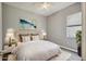 A staged bedroom with a decorative bed and a calming piece of art above it, with a view of the outdoors at 14150 Cattle Egret Pl, Lakewood Ranch, FL 34202