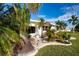 Home exterior with a beautiful landscaped yard featuring tropical plants and a green lawn at 1511 S Knollwood Dr, Bradenton, FL 34208