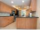 Modern kitchen with wood cabinetry, black counters and appliances, and tile flooring at 1511 S Knollwood Dr, Bradenton, FL 34208