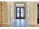 Elegant foyer with decorative glass double doors, large tiled floor and white pillars at 15403 Leven Links Pl, Lakewood Ranch, FL 34202
