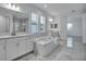 Bright bathroom with double sinks, marble-look floors, soaker tub, and large windows at 17703 Savory Mist Cir, Bradenton, FL 34211