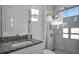 A bright bathroom with granite countertops, frameless glass shower, and mosaic tile flooring at 17703 Savory Mist Cir, Bradenton, FL 34211