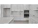 A modern kitchen featuring white cabinetry, stainless steel appliances, and neutral backsplash at 17703 Savory Mist Cir, Bradenton, FL 34211