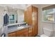 Bathroom with wood cabinetry, granite countertop, a window, and a view into the Primary bedroom at 2434 Carlisle Pl, Sarasota, FL 34231
