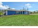 This home boasts an expansive green lawn and a blue exterior paint scheme perfectly complemented by a grey tile roof at 2434 Carlisle Pl, Sarasota, FL 34231