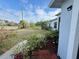 Lush front yard with blooming red flowers, manicured greenery, and a view of the street on a beautiful day at 3650 S Sumter Blvd, North Port, FL 34287
