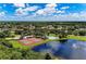 Aerial view of community amenities featuring tennis courts, a pool, and a scenic lake, perfect for active living at 5103 73Rd E St, Bradenton, FL 34203