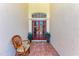 Cozy outdoor entryway with tiled floor, rattan chair, and red double doors at 5103 73Rd E St, Bradenton, FL 34203