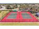 Aerial view of fenced tennis courts with red surface amidst landscaped community at 5103 73Rd E St, Bradenton, FL 34203