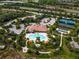 Aerial view of a community pool, clubhouse, tennis courts, landscaping, and adjacent highway at 5656 Cantucci St, Nokomis, FL 34275