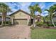 Charming single-story home with a well-manicured lawn, palm trees, and brick driveway at 5656 Cantucci St, Nokomis, FL 34275