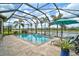 Enclosed pool with lake view, an umbrella, and tiled deck, surrounded by palm trees at 5656 Cantucci St, Nokomis, FL 34275