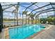 Beautiful enclosed pool with serene lake view surrounded by tropical plants and a spacious patio at 5656 Cantucci St, Nokomis, FL 34275