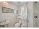 Compact bathroom featuring a glass-enclosed shower, pedestal sink, and modern fixtures at 5708 Holmes Blvd, Holmes Beach, FL 34217