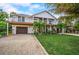 Inviting two-story home featuring tropical landscaping, a two-car garage, and elevated balconies at 5708 Holmes Blvd, Holmes Beach, FL 34217