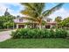 Beautiful two-story home featuring double balconies, tropical landscaping, and an oversized driveway at 5708 Holmes Blvd, Holmes Beach, FL 34217