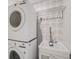 A stacked washer and dryer setup with utility sink and decorative tile backdrop creates a functional space at 5708 Holmes Blvd, Holmes Beach, FL 34217
