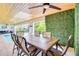 Inviting outdoor dining area by the pool with modern decor and an artificial green wall feature at 5708 Holmes Blvd, Holmes Beach, FL 34217