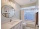 Well-lit bathroom featuring a marble vanity top, modern fixtures, and a bathtub-shower combo with window and privacy blinds at 6684 Easton Dr, Sarasota, FL 34238