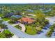 Expansive aerial view of a luxurious, red-tiled home with lush landscaping and a circular driveway in a serene, tree-lined neighborhood at 6900 Country Lakes Cir, Sarasota, FL 34243