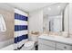 Well-lit bathroom featuring a shower and vanity with a white-and-blue striped curtain at 1001 Beach Rd # A203, Sarasota, FL 34242
