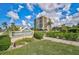 Beautiful condominium building, Our House at the Beach, featuring lush landscaping and blue skies in a tropical location at 1001 Beach Rd # A203, Sarasota, FL 34242