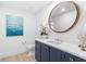 Elegant bathroom with navy cabinets, white countertops, and a decorative round mirror at 1035 Seaside Dr # 603, Sarasota, FL 34242