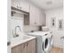 Well-lit laundry room featuring modern appliances, ample counter space, overhead cabinets, and tile flooring at 1035 Seaside Dr # 603, Sarasota, FL 34242