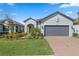 Charming single-story home featuring a manicured lawn, brick driveway, and gray exterior with a two car garage at 11127 Devonbridge Dr, Palmetto, FL 34221