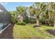 Grassy backyard is framed by lush palm trees, complemented by landscaping around the screened pool at 12370 Marsh Pointe Rd, Sarasota, FL 34238