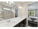 Bathroom featuring double sinks, dark cabinetry, and a mirror reflecting the bedroom and shower area at 12370 Marsh Pointe Rd, Sarasota, FL 34238