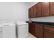 Bright laundry room with modern washer and dryer, and wooden cabinets with dark countertops at 13065 Bliss Loop, Bradenton, FL 34211