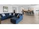 Open concept living room boasts a large blue sectional, neutral tile flooring and an adjacent kitchen at 13065 Bliss Loop, Bradenton, FL 34211