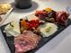 Arrangement of cured meats, cheeses, and fruit on a black serving board at 14671 Derna Ter, Bradenton, FL 34211