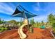 Community playground featuring a slide, climbing structure, and shaded seating area on a mulched play surface at 15008 Trinity Fall Way, Bradenton, FL 34212