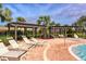 Lounge chairs and tables surround a community pool with trellises and beautiful palm trees on the patio at 15008 Trinity Fall Way, Bradenton, FL 34212