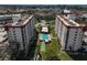 An aerial view showcasing the condominium buildings with community pool, tennis court, parking, and landscaping at 244 Saint Augustine Ave # 905, Venice, FL 34285