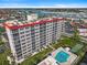 An aerial view showcasing the condominium building with pool, shuffleboard, landscaping, and marina in the distance at 244 Saint Augustine Ave # 905, Venice, FL 34285