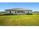 View of the home's backyard featuring an enclosed sunroom and well-kept lawn at 25259 Alcazar Dr, Punta Gorda, FL 33955
