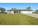 Beautiful single-story home with a three-car garage, green lawn, and a striking red front door at 25259 Alcazar Dr, Punta Gorda, FL 33955